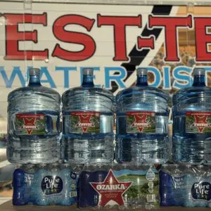 A group of water bottles and cans sitting on top of the ground.
